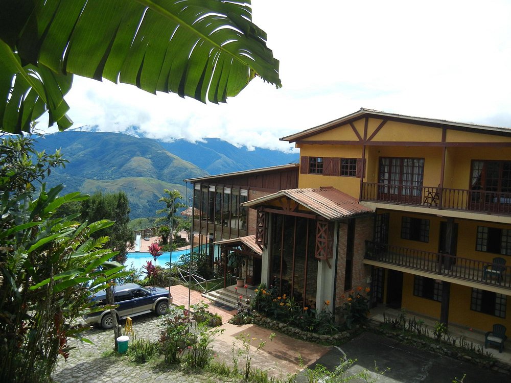 Edificio principal del hotel entre la vegetación, con la cordillera de fondo